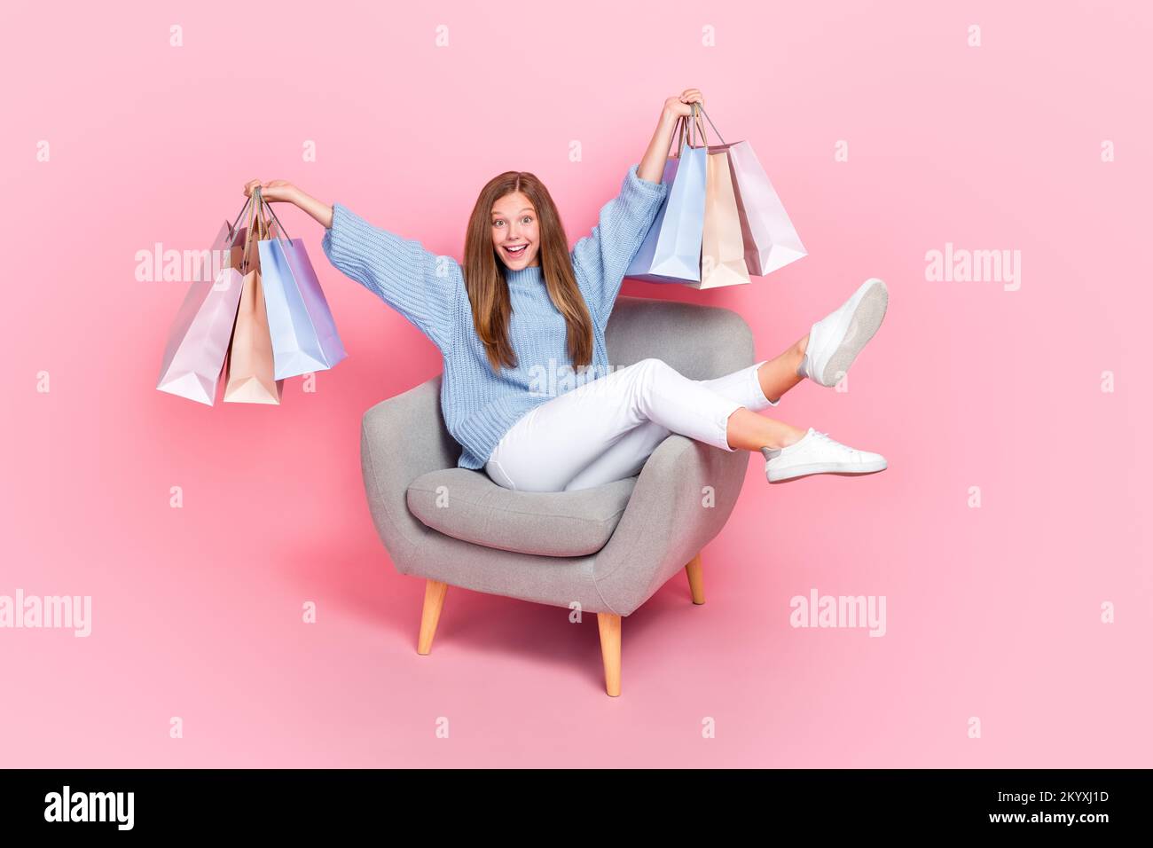 Langes Foto von einem flippigen Teenager mit einer jungen Shopaholic Lady trägt blaue Strickmode Pullover Haltebeutel Sit Relax Couch isoliert auf pinkfarbenem Hintergrund Stockfoto