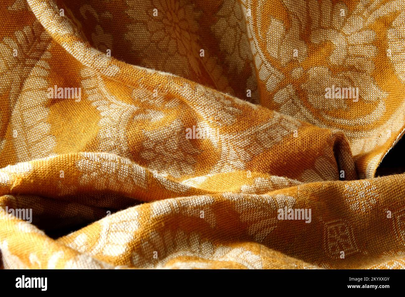Drapierter goldener Stoff mit natürlichem Blattmuster - Textilhintergrund Stockfoto