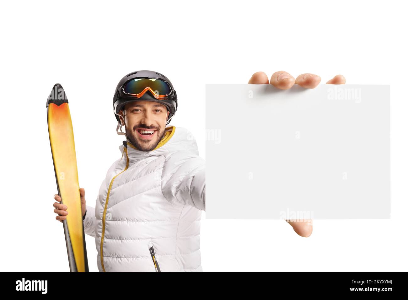 Männlicher Skifahrer, der Skifahrer hält und einen kleinen leeren Karton auf weißem Hintergrund zeigt Stockfoto