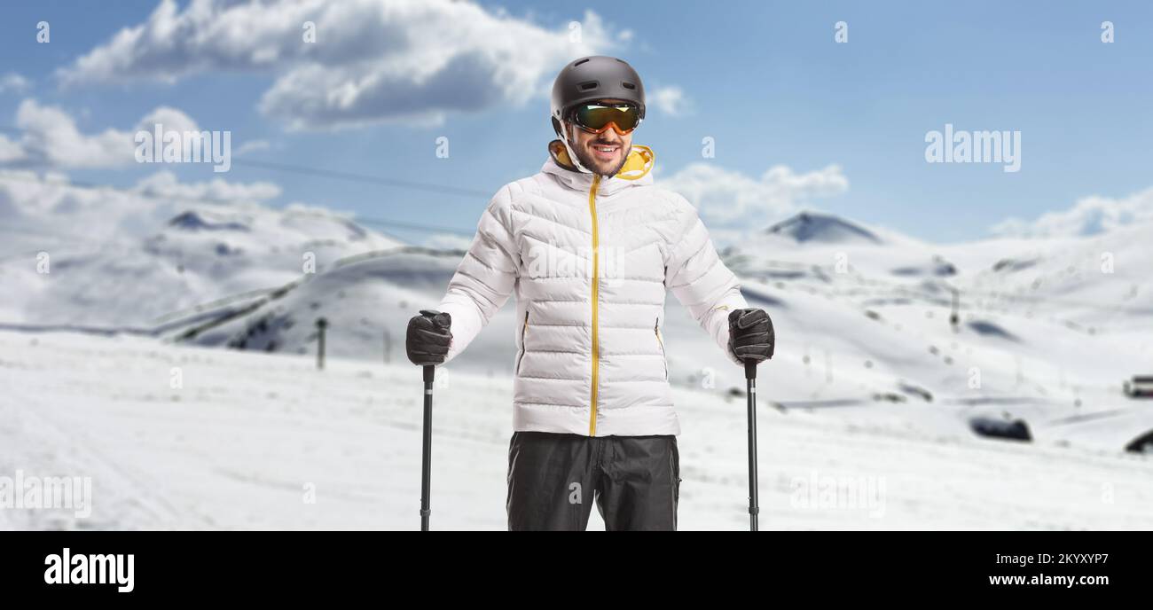 Männlicher Skifahrer mit Helm und Schutzbrille, der in einem Skigebiet posiert Stockfoto