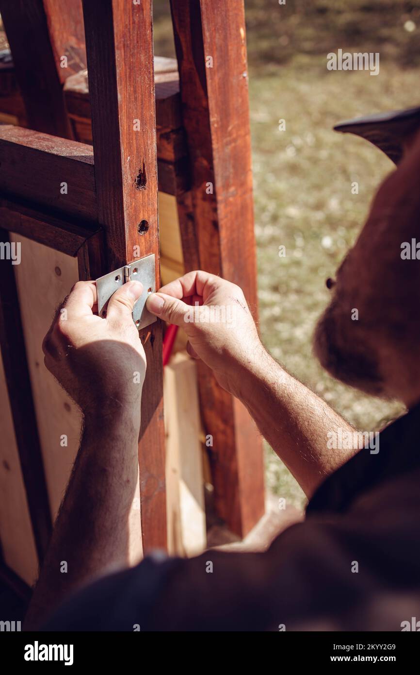 Handwerker, der ein Türscharnier in den hölzernen Türrahmen legt. Hausrenovierung Stockfoto
