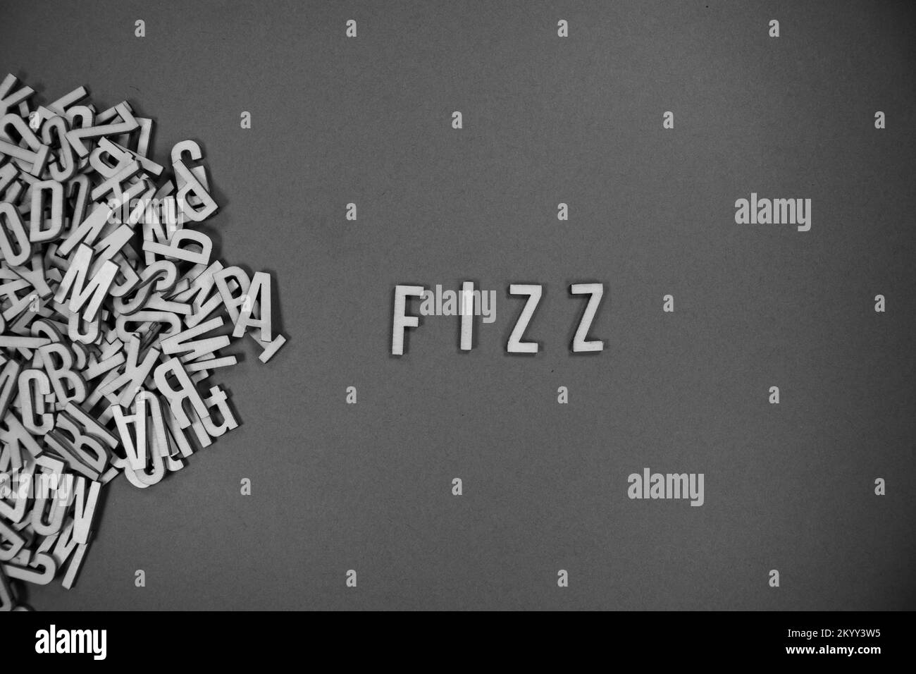 Ein Haufen englischsprachiger Großbuchstaben aus Holz, die in Worte fließen - FIZZ in Schwarz und Weiß Stockfoto