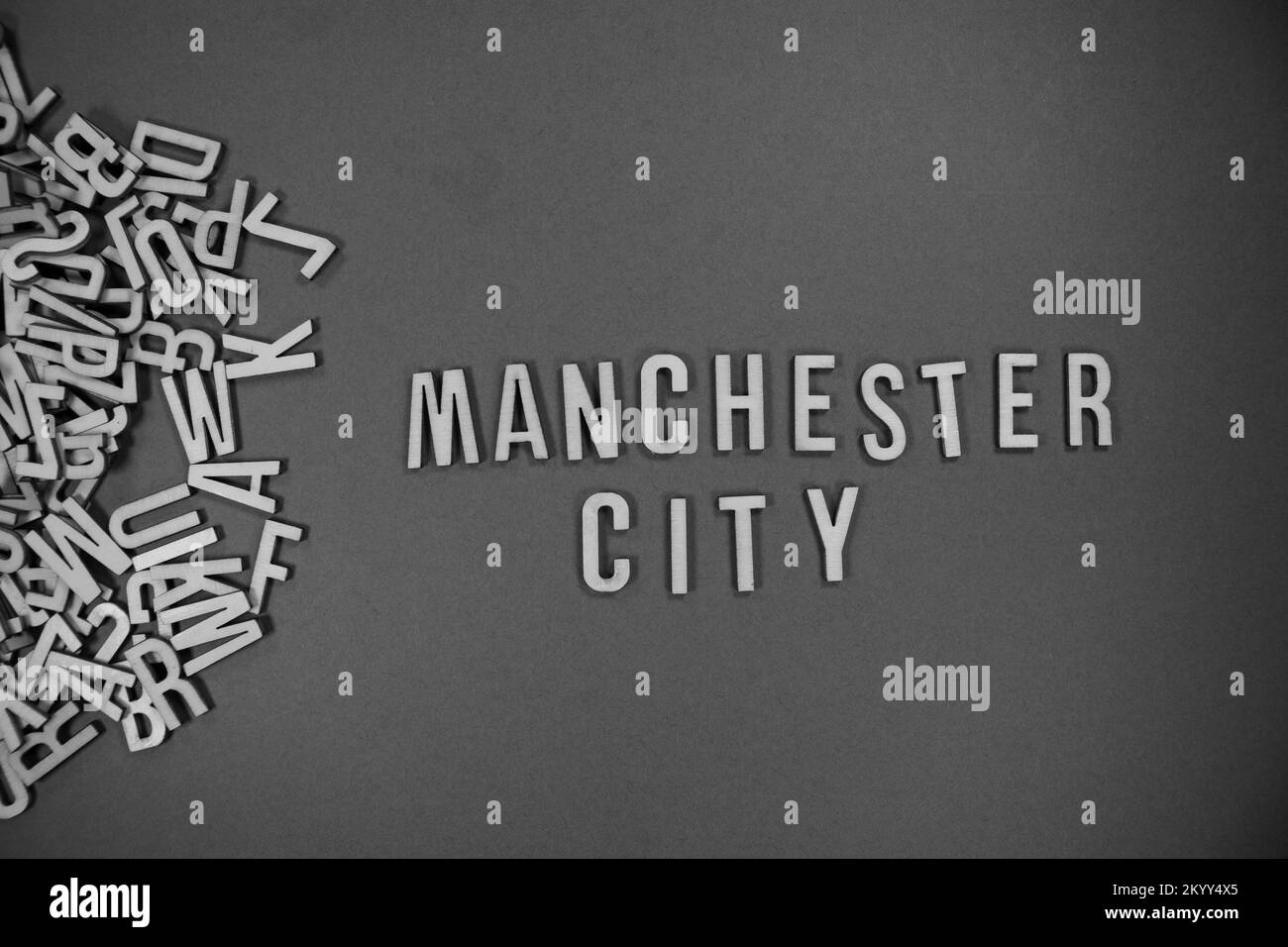 Ein Haufen englischsprachiger Großbuchstaben aus Holz, die in Worte fließen - MANCHESTER CITY in Schwarz und Weiß Stockfoto