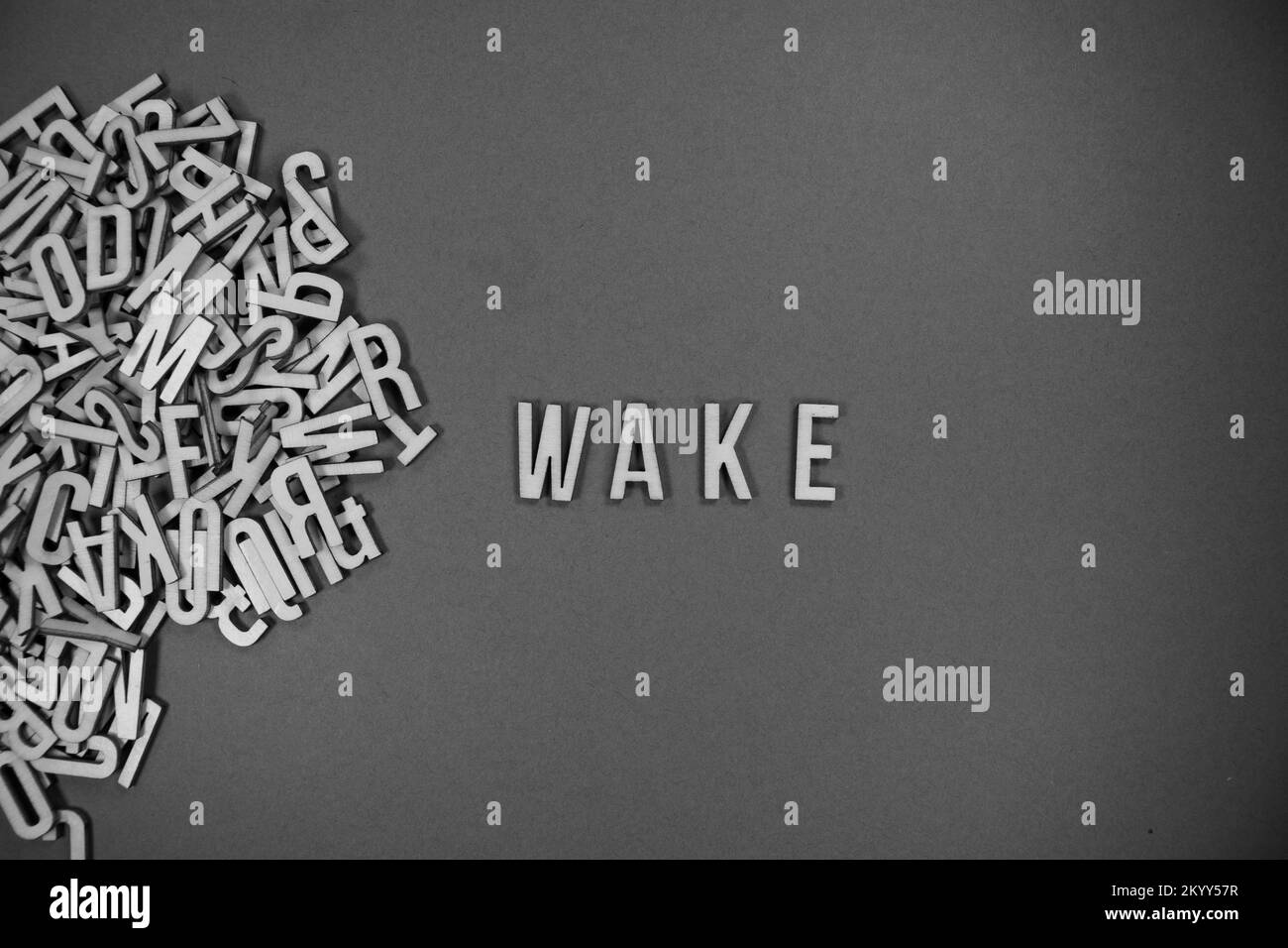 Ein Haufen englischsprachiger Großbuchstaben aus Holz, die in Worte fließen - WACHEN Sie in Schwarz und Weiß AUF Stockfoto