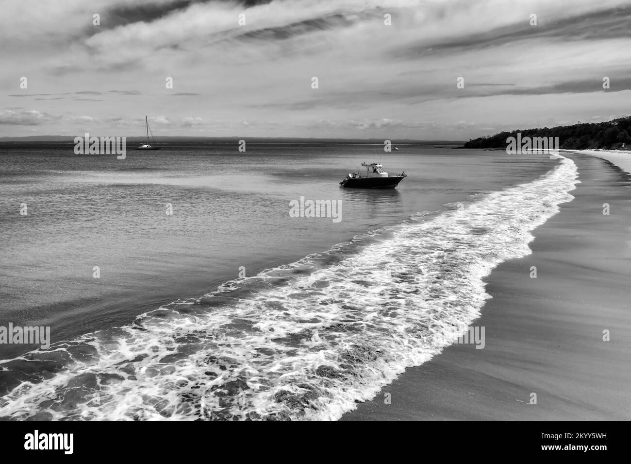 Hoher Kontrast in Schwarz-Weiß - kleines Motorboot auf weißem Sand am langen Strand in Jervis Bay Pazifikküste Australiens - Luftparadies Meereslandschaft. Stockfoto