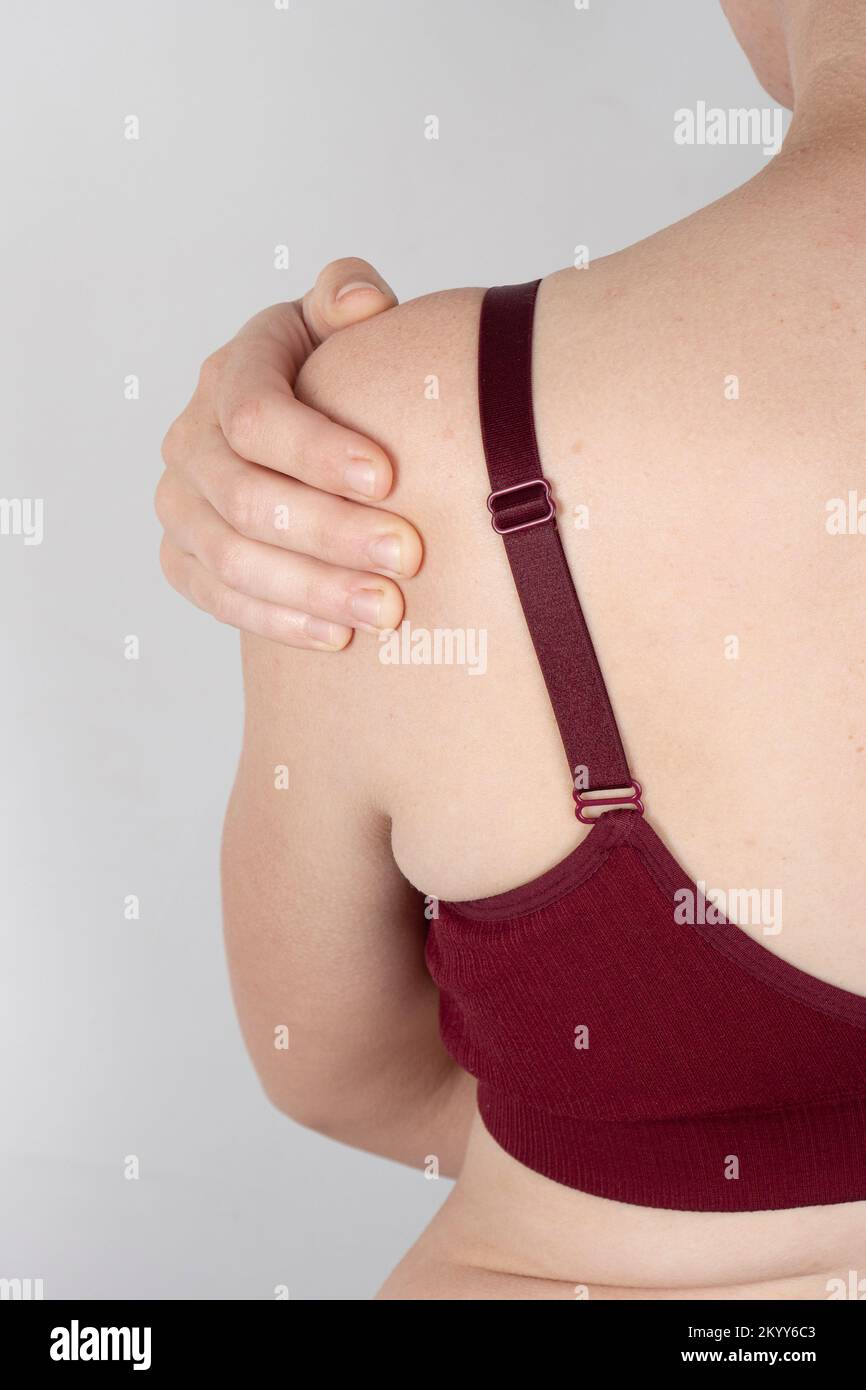 Eine Frau in einem Sport-BH hält ihre schmerzende Schulter und dehnte Sehnen am Unterarm. Stockfoto