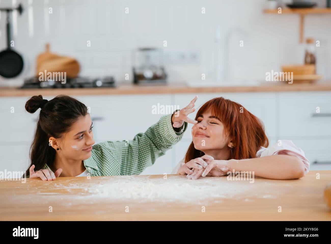 Zwei schöne Frauen spielen mit Mehl in der Küche Stockfoto