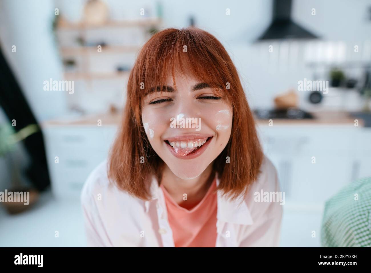 Verspielte junge Frau mit Geschmack im Gesicht in der Küche Stockfoto