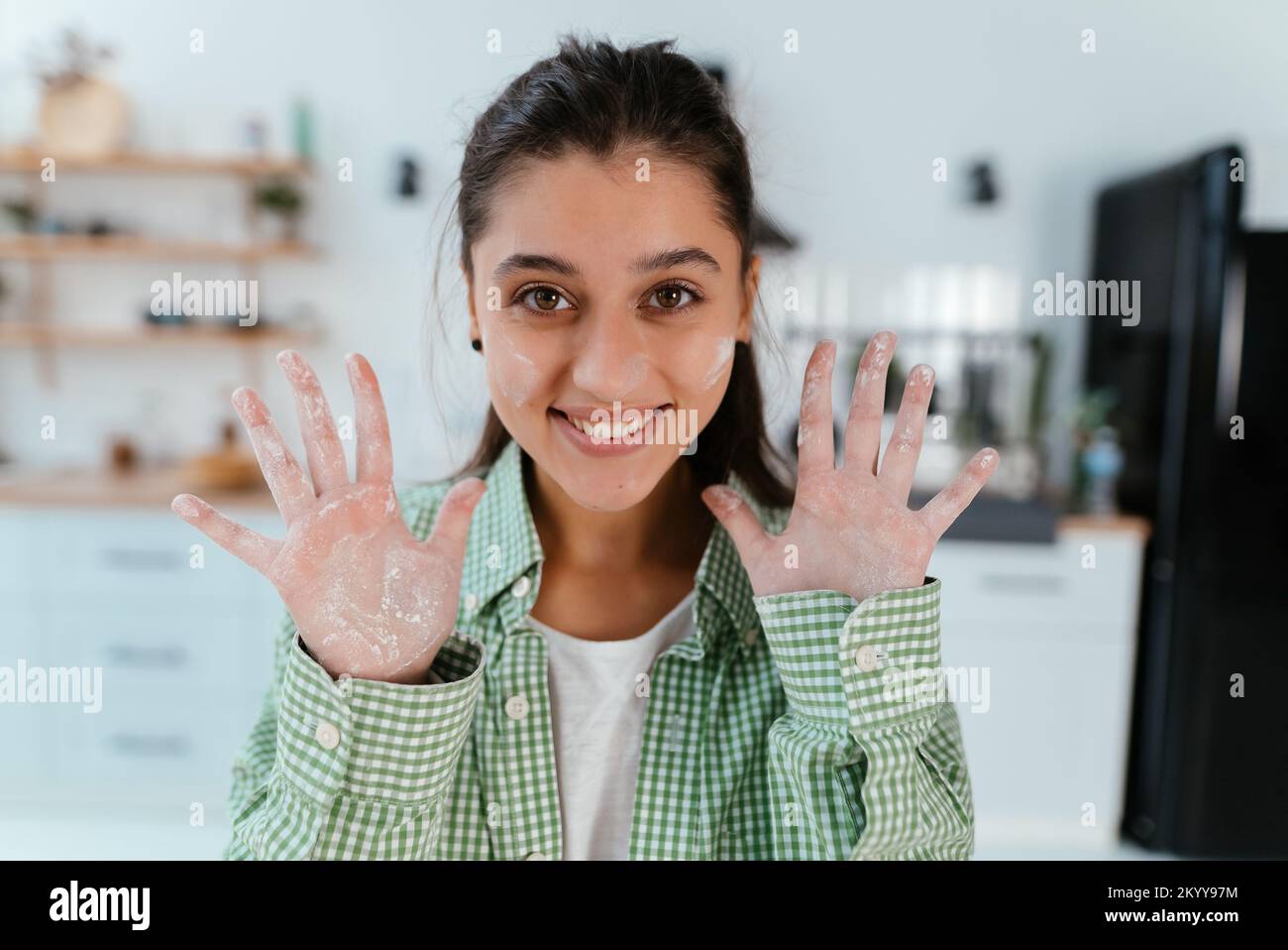 Junge Frau zeigt ihre Hände in Mehl in der Küche Stockfoto