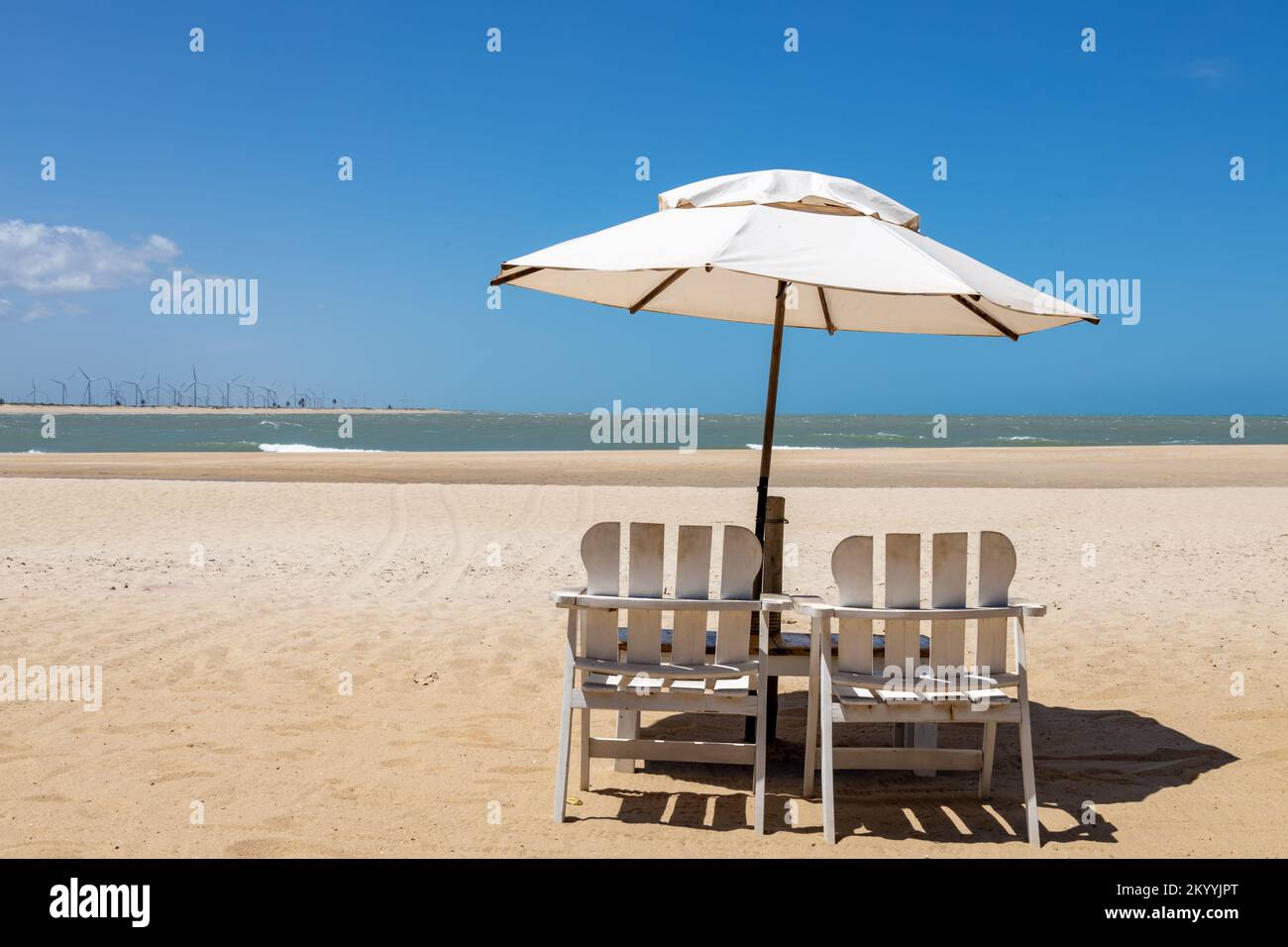 Holzstühle und ein Sonnenschirm an einem tropischen Strand an einem sonnigen Tag. Paradies am Strand. Urlaubskonzept. Stockfoto