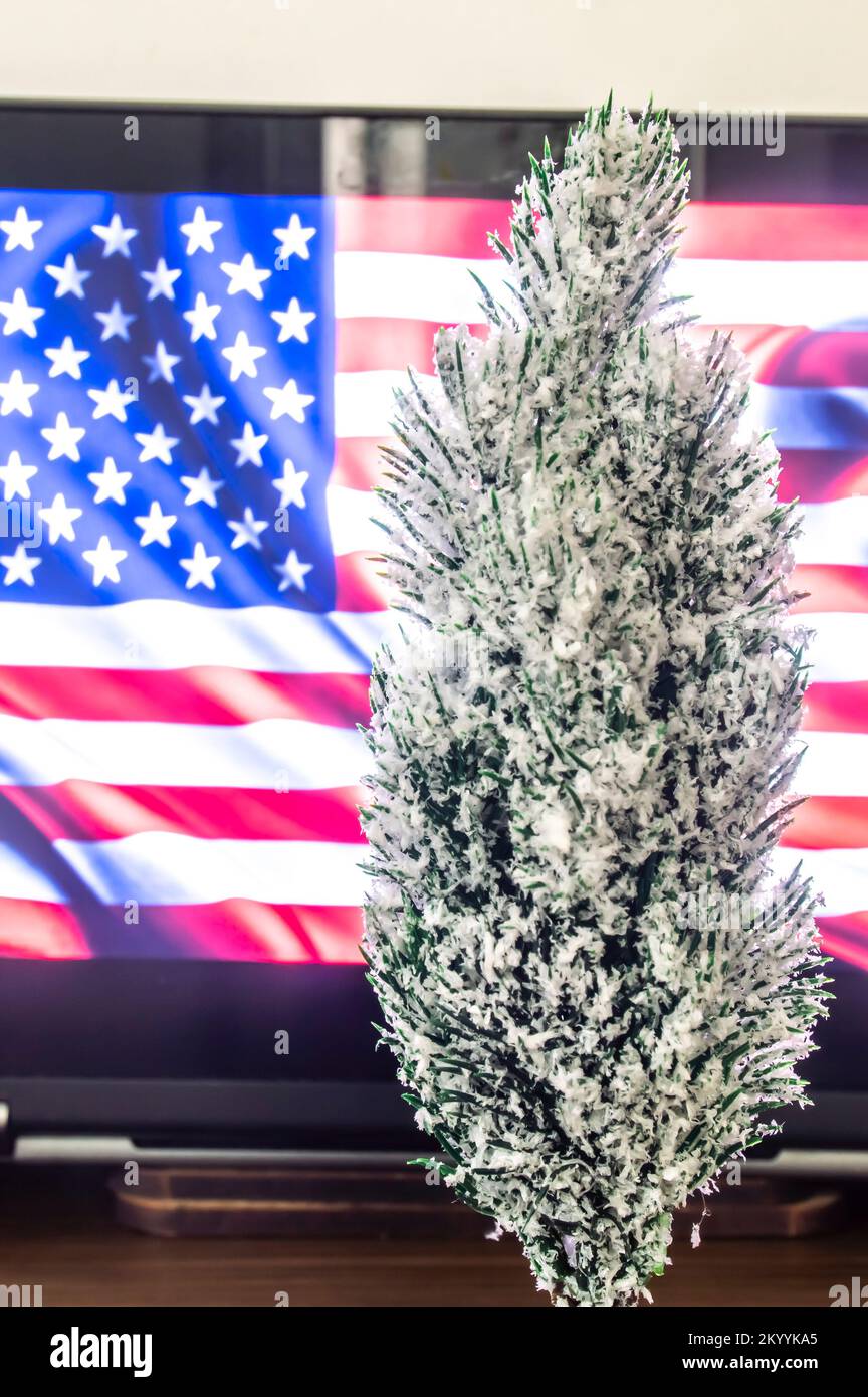 Weihnachtsbaum mit Computer im Hintergrund und US-Flagge auf dem Bildschirm. Stockfoto