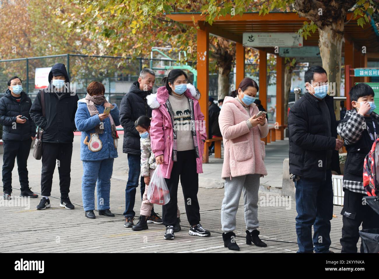 FUYANG, CHINA - 3. DEZEMBER 2022 - Menschen stellen sich für kostenlose Nukleinsäuretests in einer lokalen Nukleinsäureteststelle für COVID-19 in Fuyang, an Stockfoto