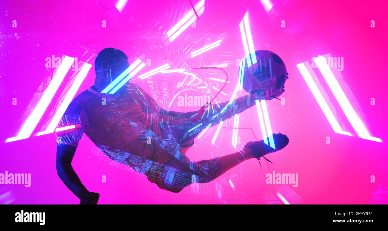 Ein afroamerikanischer Spieler springt und tritt den Ball über beleuchtete Linien auf pinkfarbenem Hintergrund Stockfoto