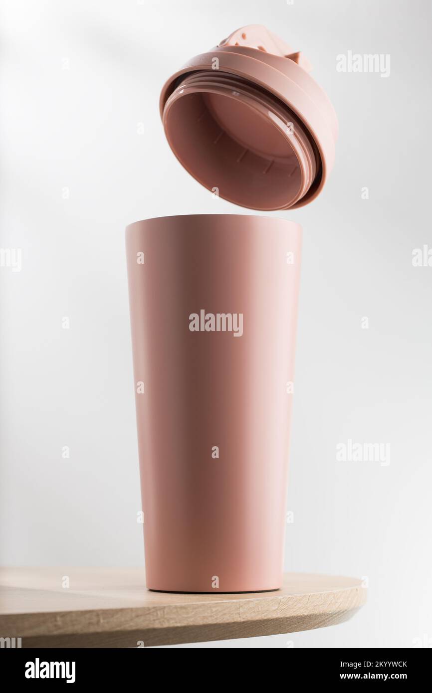 Rosafarbener Becher oder Thermos auf Holztisch Stockfoto