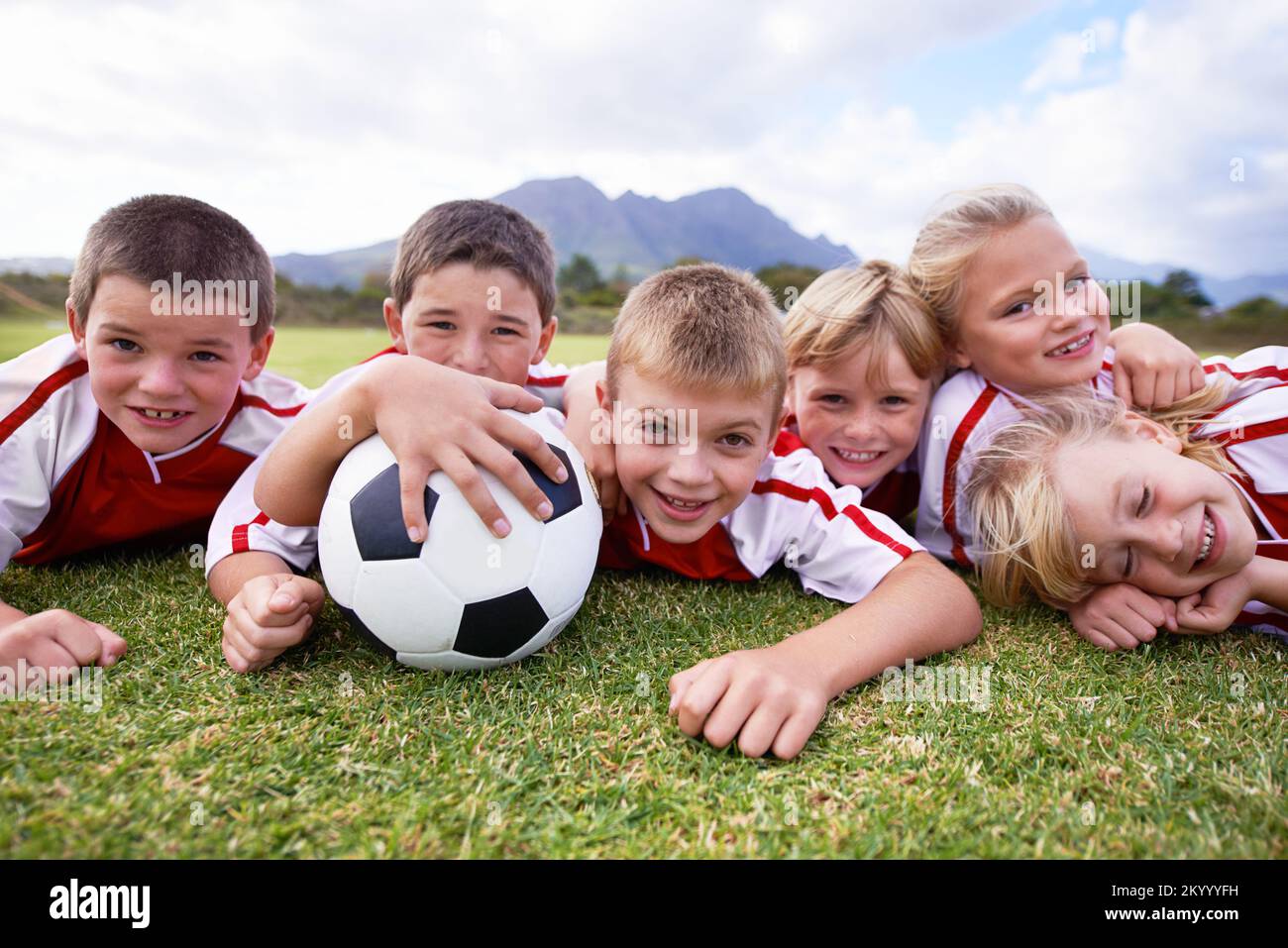 Nach dem Training ist es Zeit zum Entspannen. Porträt einer Kinderfußballmannschaft, die auf dem Spielfeld liegt. Stockfoto