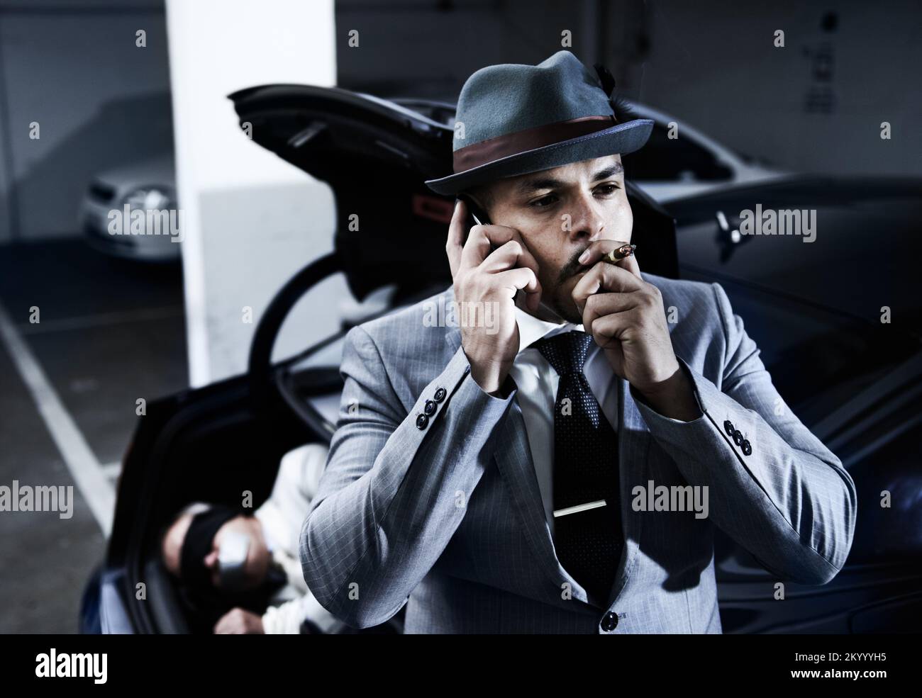 Der Job, der jetzt erledigt ist, wo mein Anteil liegt... Ein Mafioso, der eine Zigarre nimmt und nach einer erfolgreichen Entführung auf seinem Handy spricht. Stockfoto