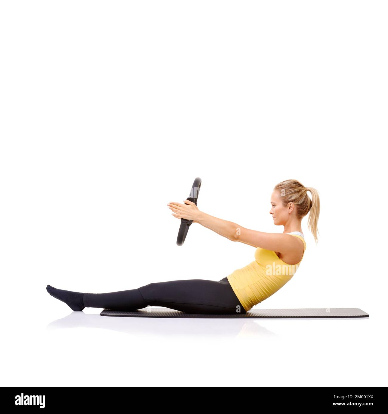 Roll-up-Übung mit ihrem Pilates-Ring. Eine hübsche, junge Blondine, die die Roll-Up-Übung mit ihrem Pilates-Ring durchführt. Stockfoto