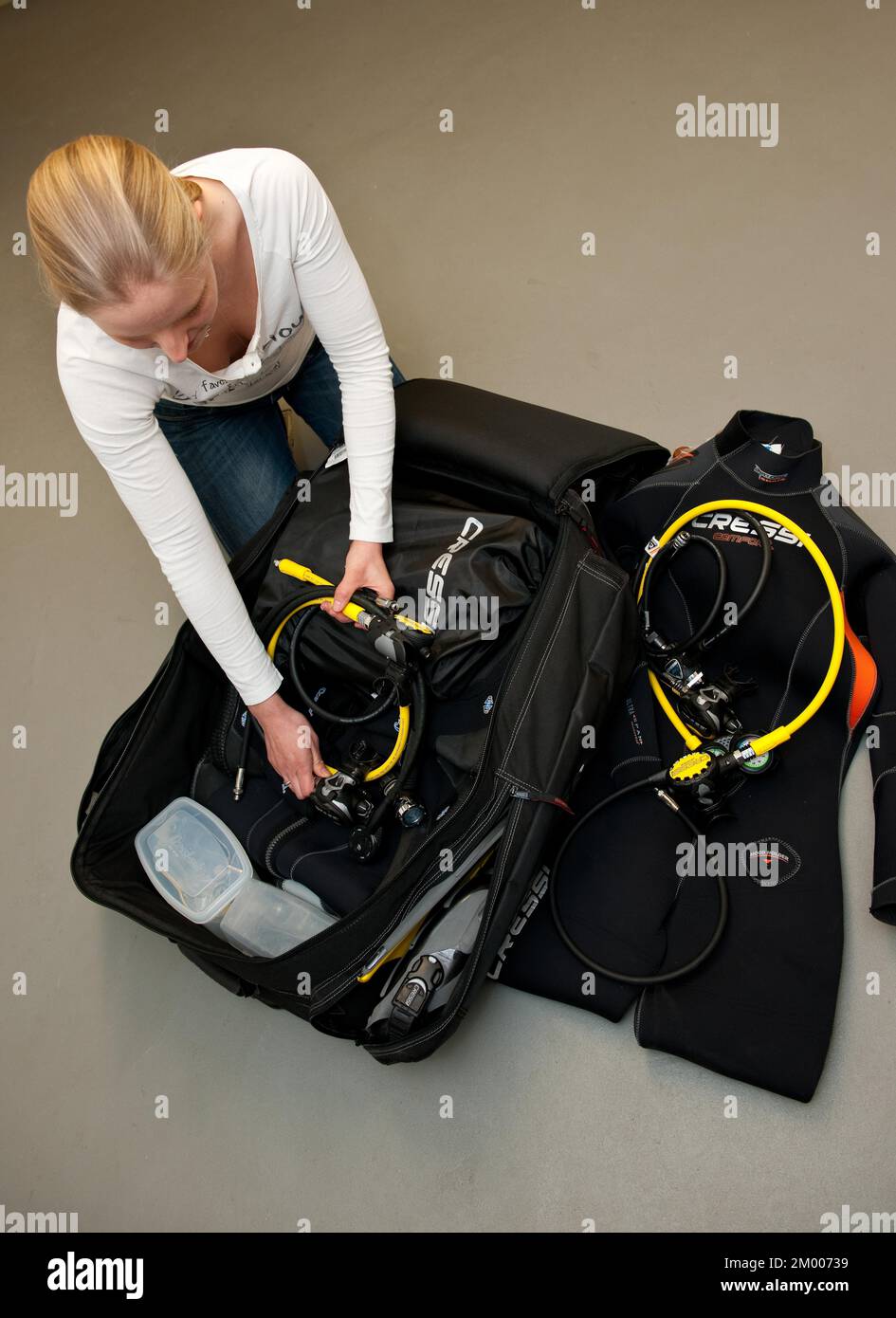 Junge Frau, die Koffer mit Tauchgepäck mit maximalen Abmessungen für Sportgepäck in einem Charterflugzeug für Flugreisen, Deutschland, Europa packt Stockfoto