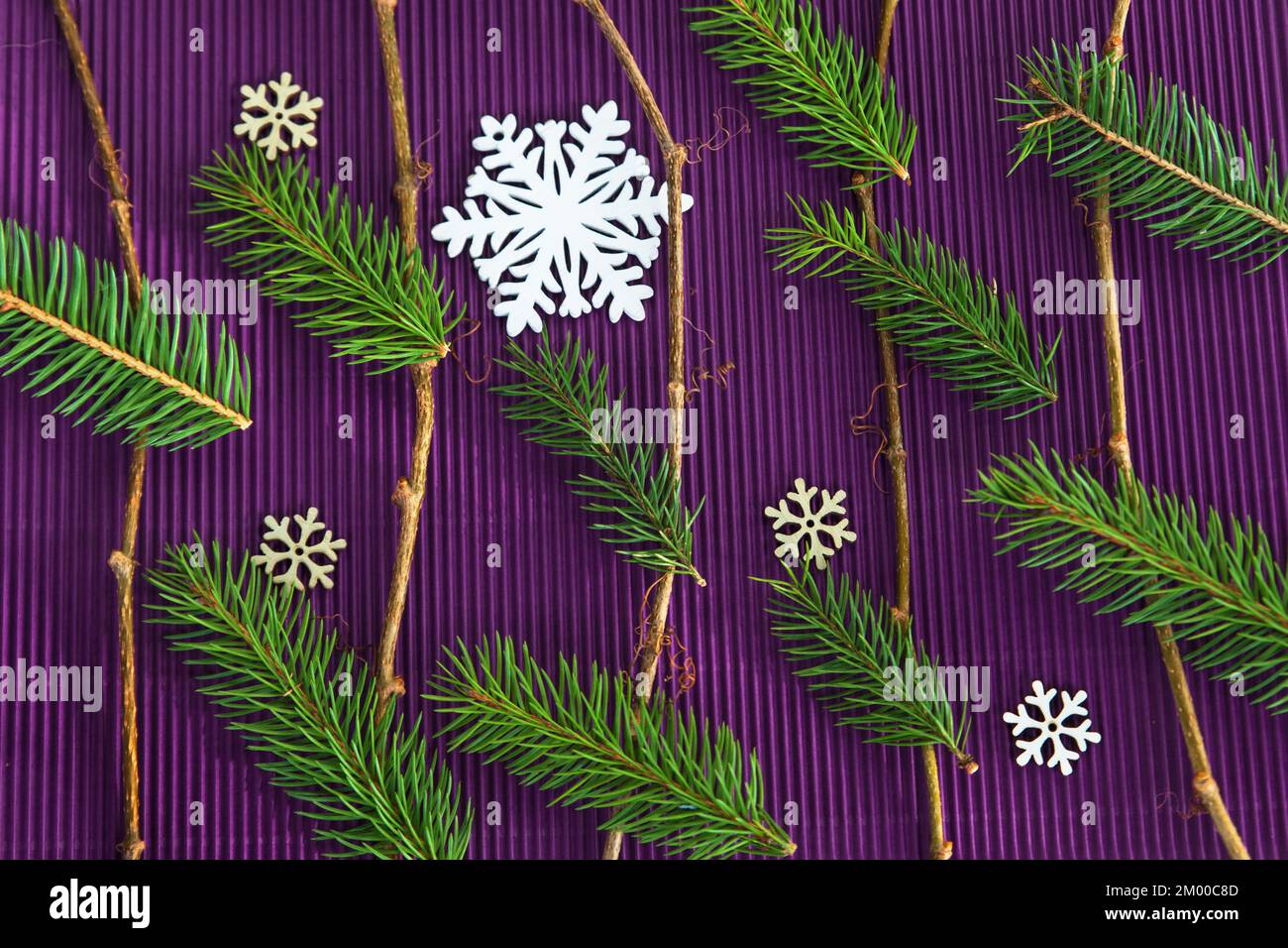 Weihnachtsgarderobe mit Zweigen und Nadeln und dekorativen Schneeflocken auf violettem Hintergrund. Stockfoto