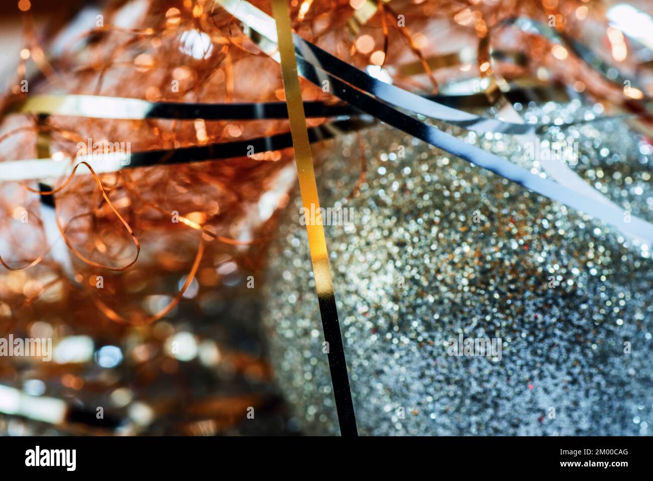 Hintergrund für Weihnachtsdekoration mit unscharfer blauer Kugel und rot-goldenem Metallfaden. Stockfoto