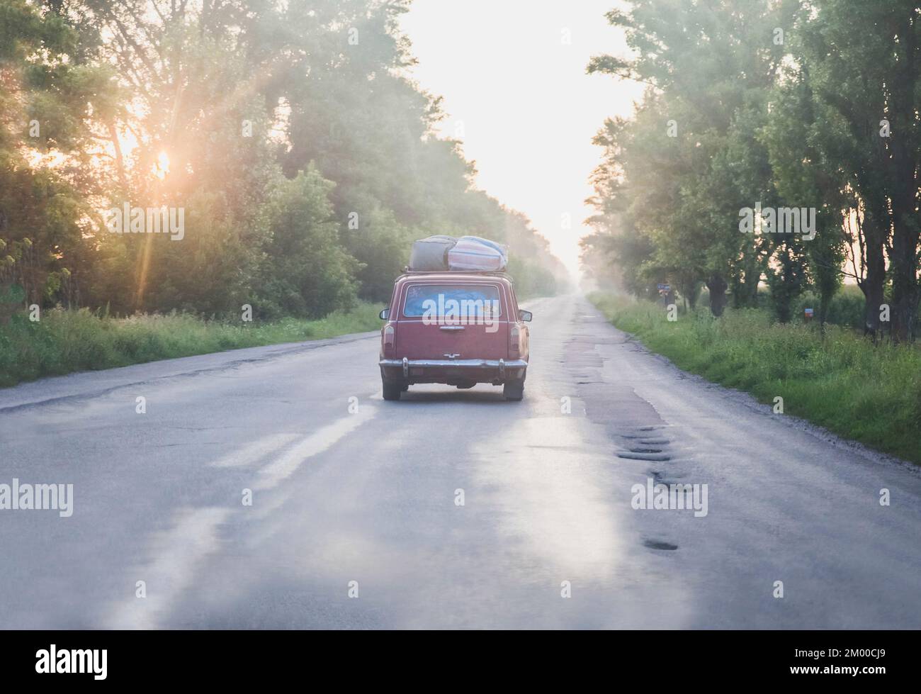 Ein altes sowjetisches Auto bei Sonnenaufgang auf einer kaputten Wüstenstraße Stockfoto