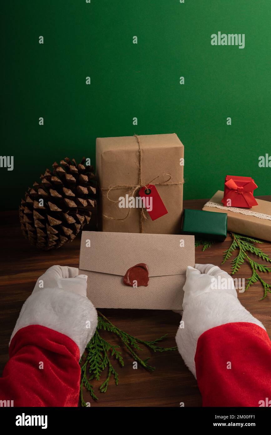 Der Weihnachtsmann liest am Heiligabend vor einer grünen und holzgrünen Kulisse Kinderwünsche Stockfoto