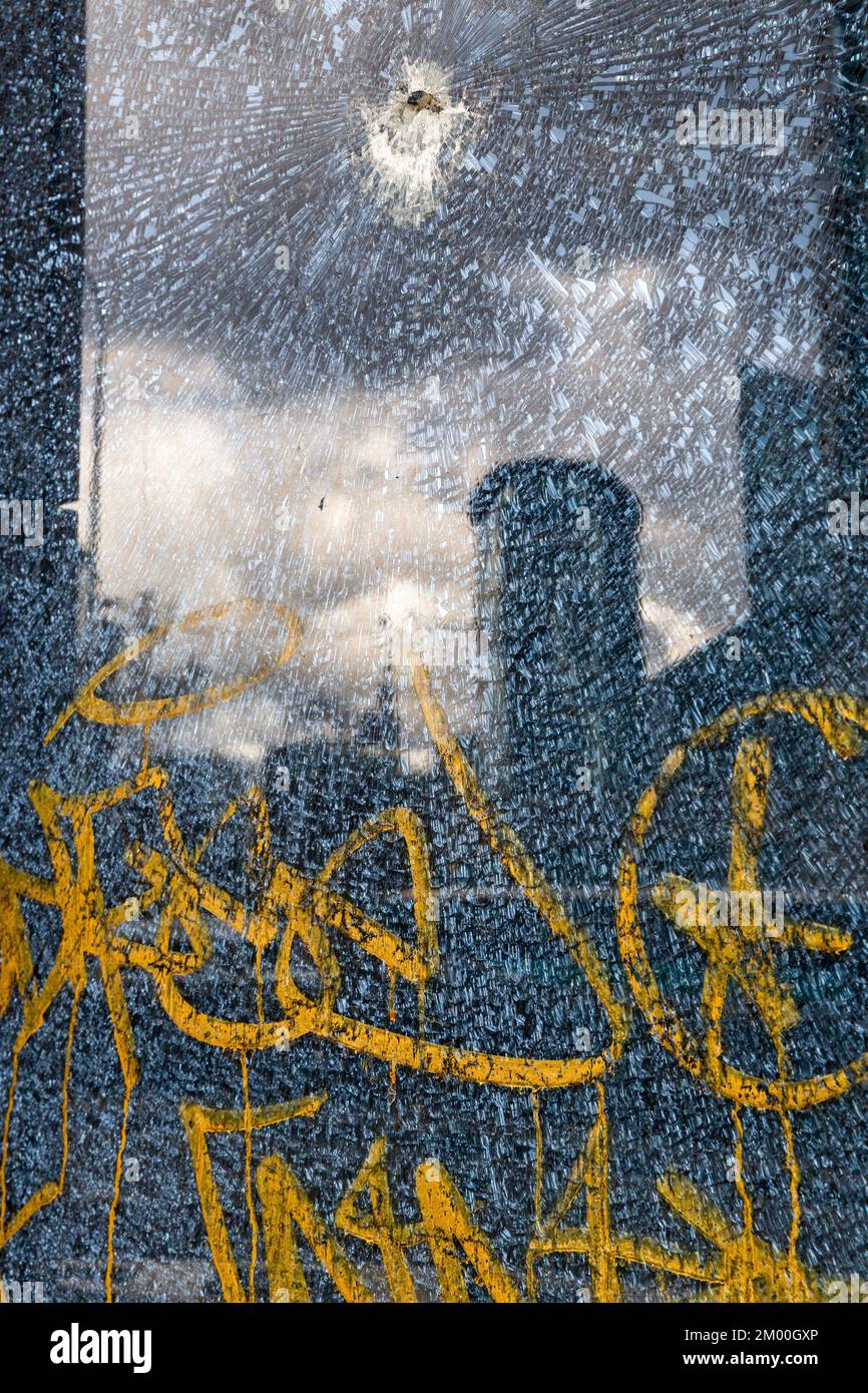 Die Auswirkungen: Stadtbild durch Reflexion auf zerbrochenem Glas, mit einem gelb-orangefarbenen Schild. Brüssel. Stockfoto