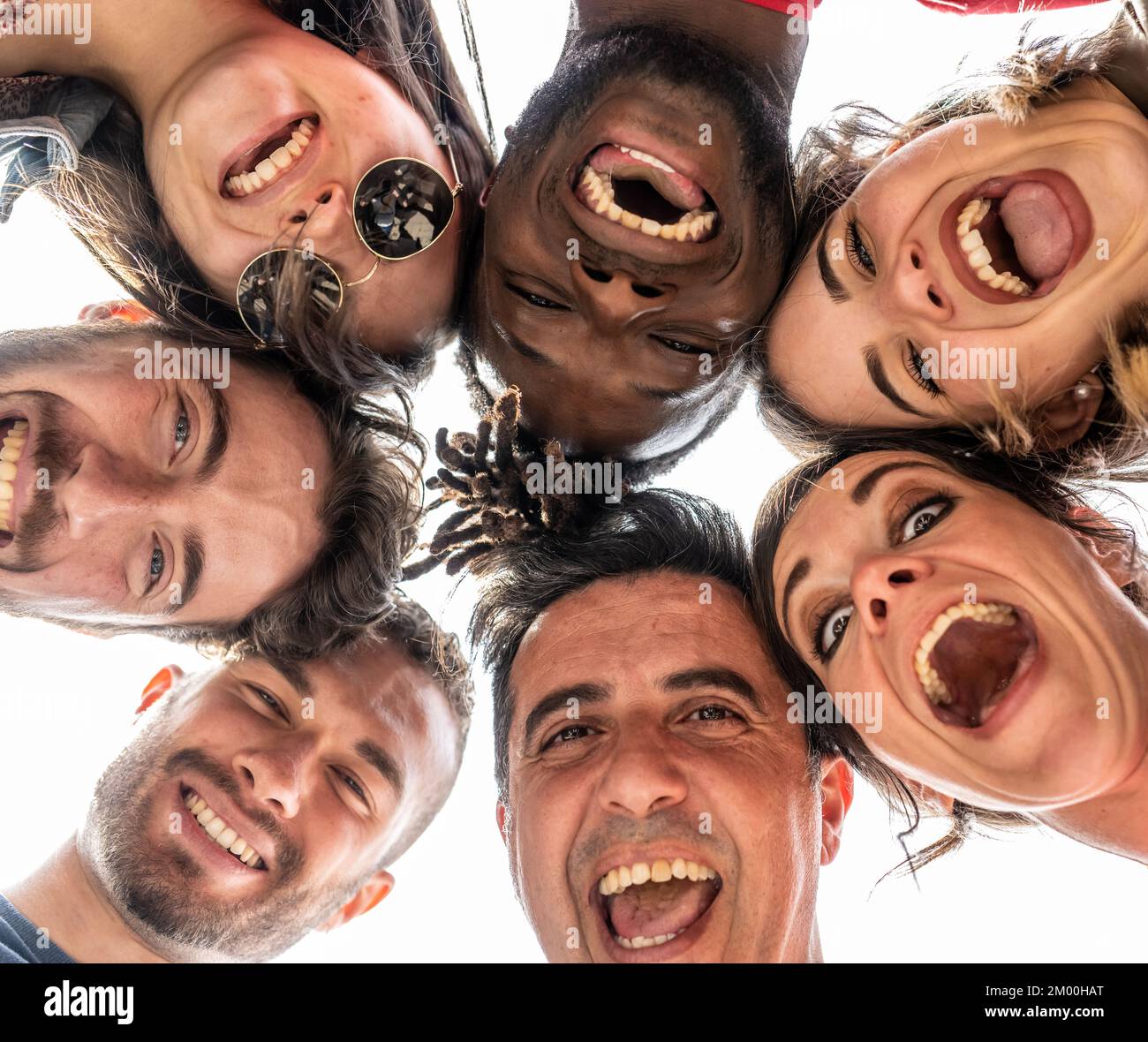 Junge Leute, die in die Kamera schauen und lachen, multirassische Gruppe von Freunden, die im Kreis stehen und vor der Kamera lächeln, Selfie-Kreis mit unterschiedlicher ethnischer Herkunft Stockfoto