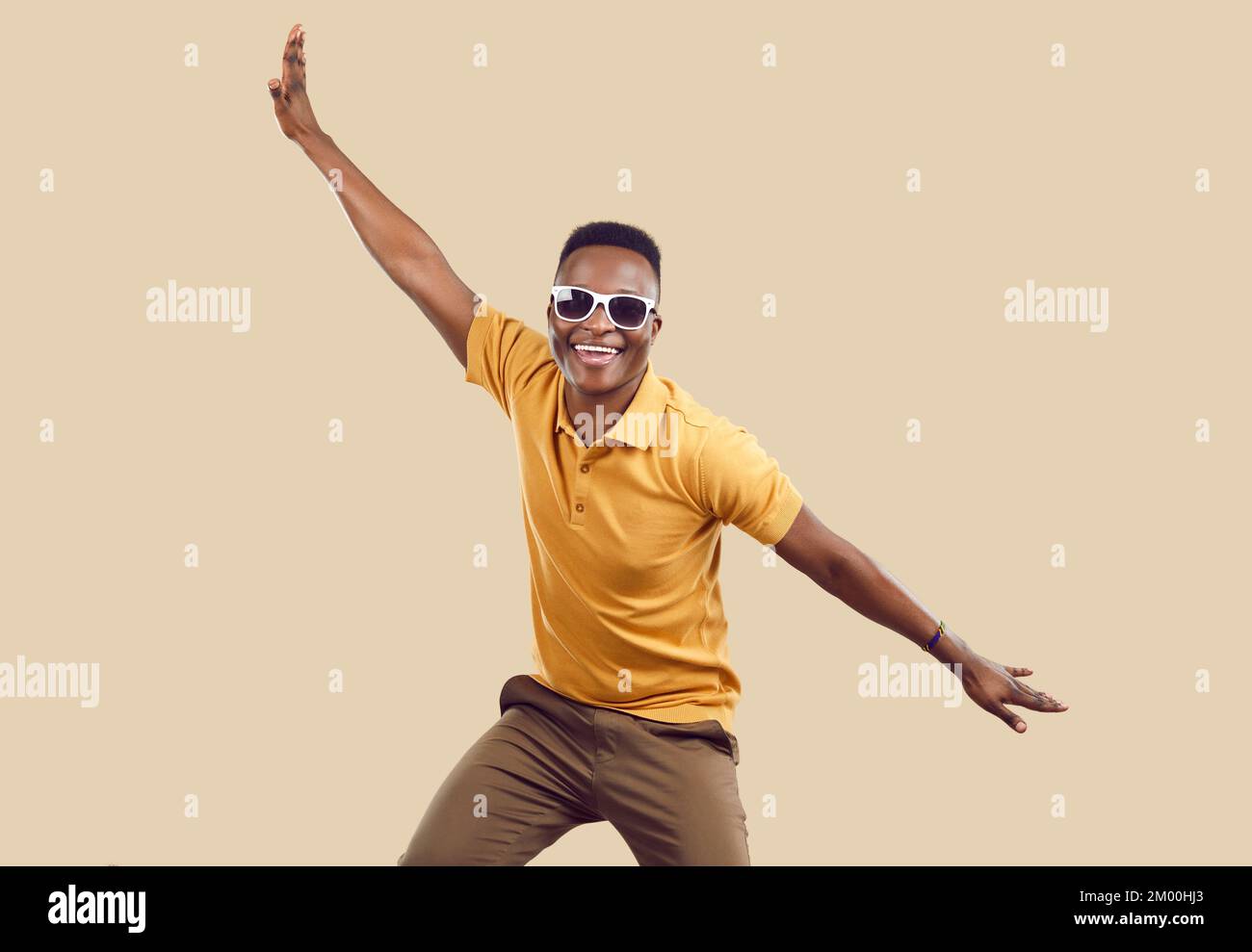 Fröhlicher, lustiger afroamerikanischer Mann mit guter Laune, der Spaß isoliert auf beigefarbenem Hintergrund hat. Stockfoto