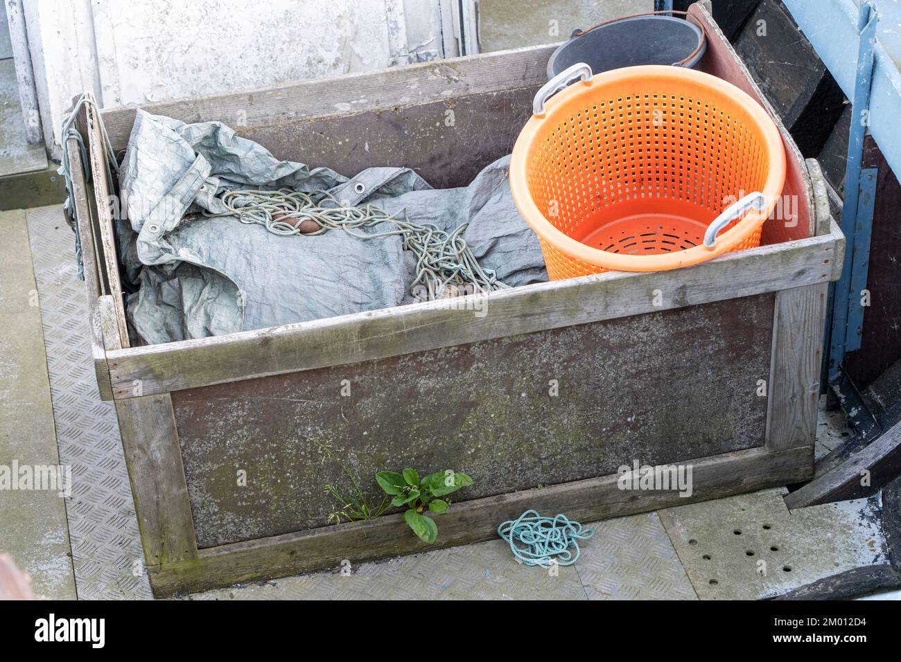 Bild: Seil, Fischnetz und orangefarbener Eimer in der Holzbox des Fischerboots Stockfoto