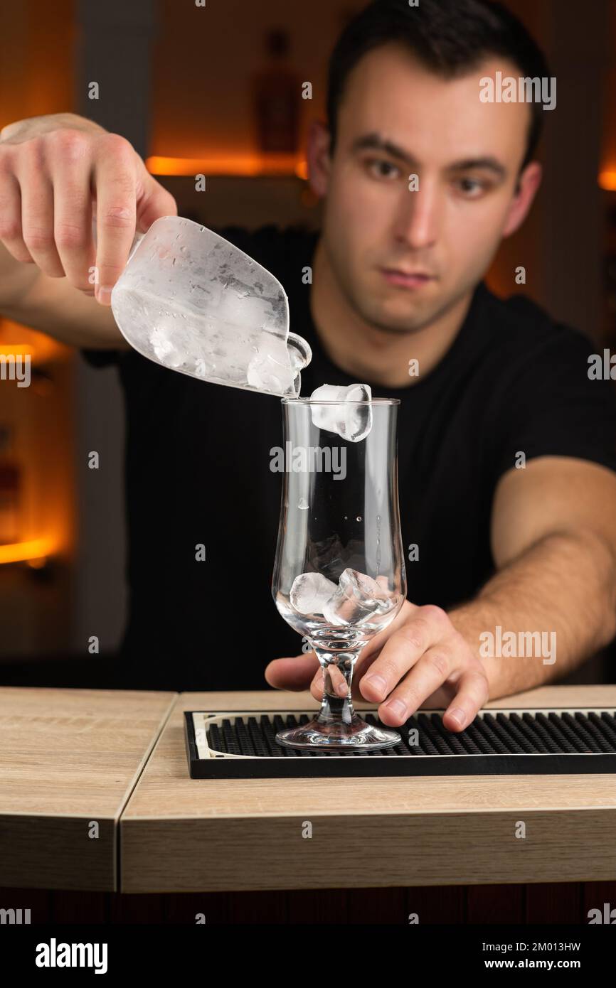 Der Barkeeper schüttet gebrochenes Eis in ein Glas. Speicherplatz kopieren Stockfoto