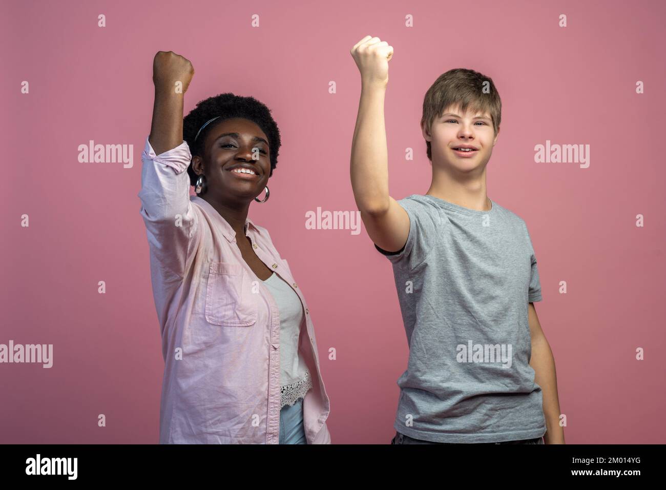 Team. Eine afroamerikanische Frau und ein Kaukasier mit DownSyndrom mit erhobener Faust, die
