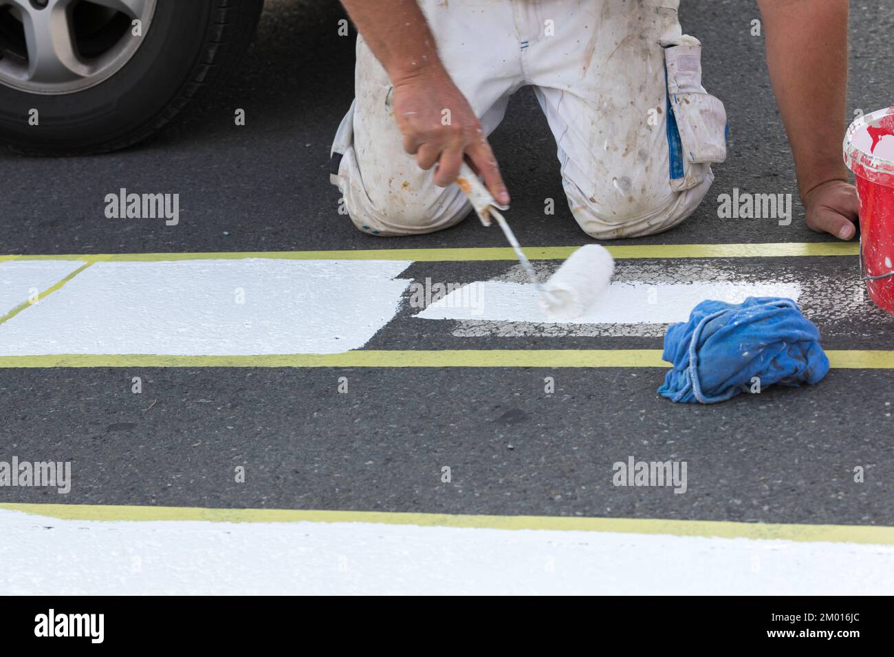 Die Straßenmarkierung wird mit einer Rolle angebracht Stockfoto