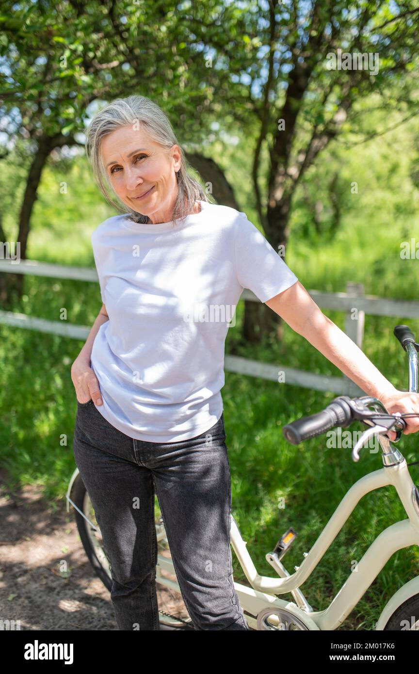 Gute Laune. Eine Frau mit einem Fahrrad, das glücklich und positiv aussieht. Stockfoto