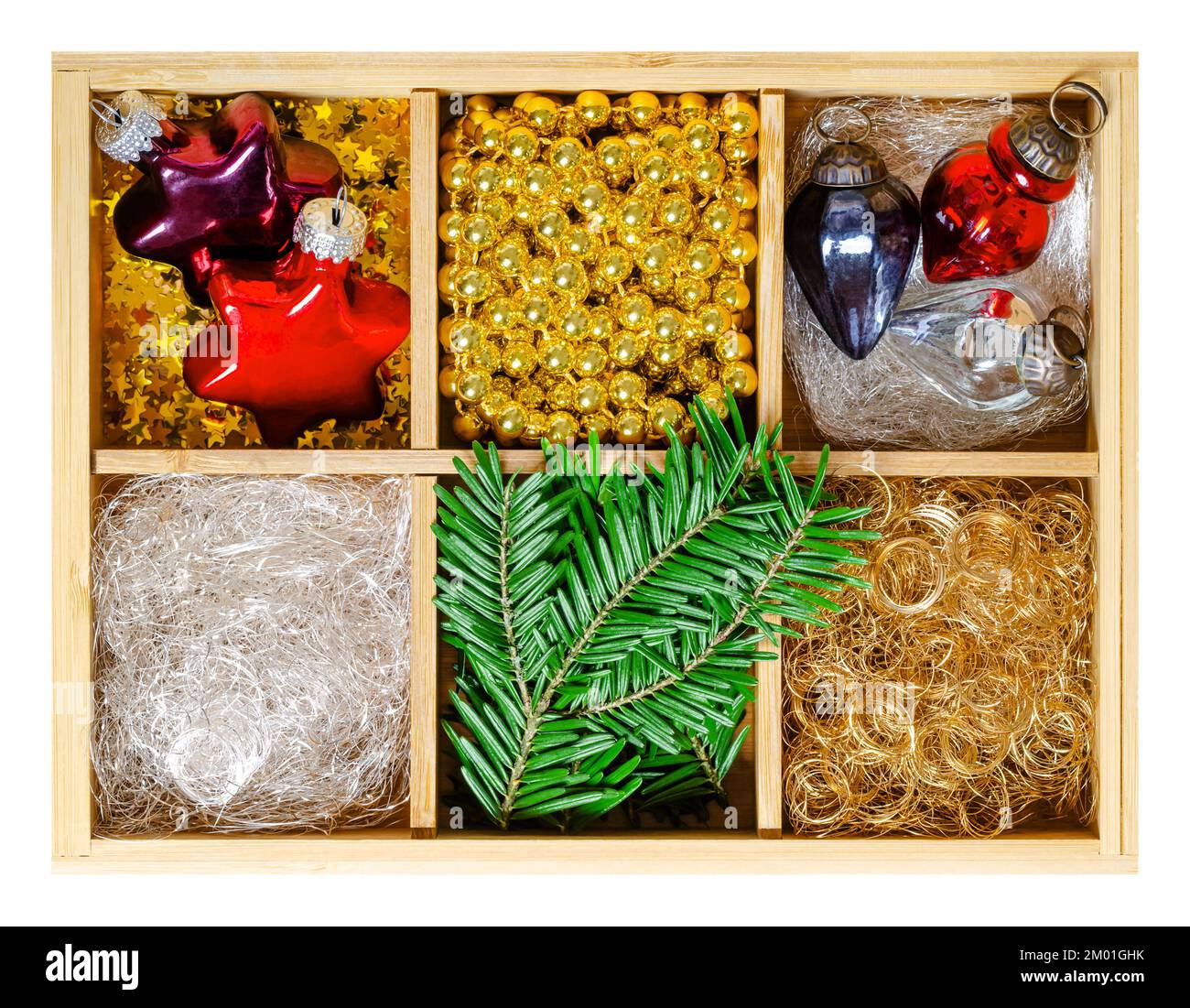 Weihnachtsschmuck in Holzkiste. Stern- und Eichelförmige Weihnachtsglaszwiebeln, silberne und goldene Engelhaare, goldene Perlengürtel und Tannenzweige. Stockfoto