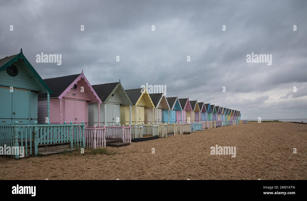 Strandhütten auf Mersea Island in Essex. Moody, bewölkter Himmel und Langzeitaufnahme. Stockfoto