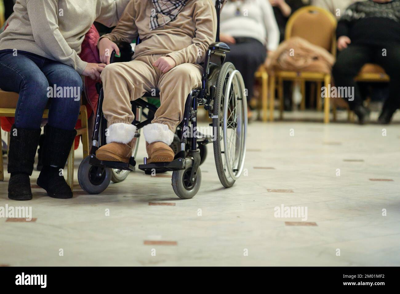 Geringe Schärfentiefe (selektiver Fokus) Details bei einer Frau im Rollstuhl während einer Tagung. Stockfoto