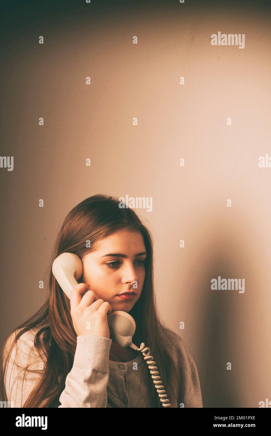 Junge Frau, die mit einem Retro-Telefon mit Kabel und Mikrofon spricht Stockfoto