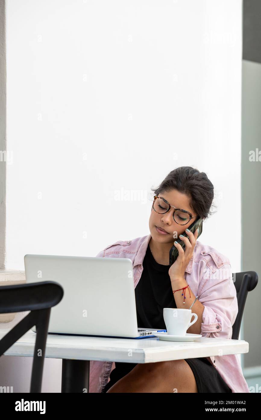 Junge lateinische Frau mit Laptop sitzt im Straßencafé - Stockfoto Stockfoto