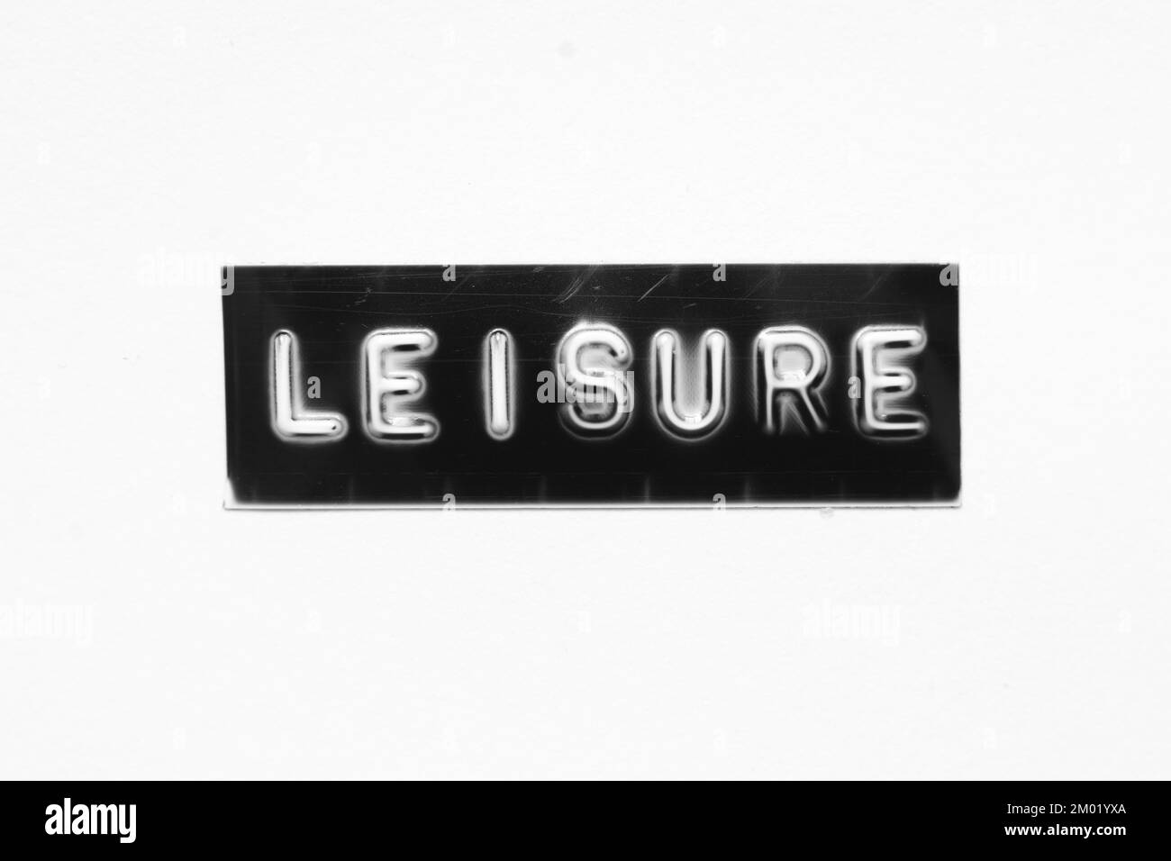 Schwarzes Banner mit geprägtem Buchstaben und Wort „Leisure“ auf weißem Papierhintergrund Stockfoto Schwarzes Banner mit geprägtem Buchstaben und Wort „Leisure“ auf weißem Papierhintergrund Stockfoto