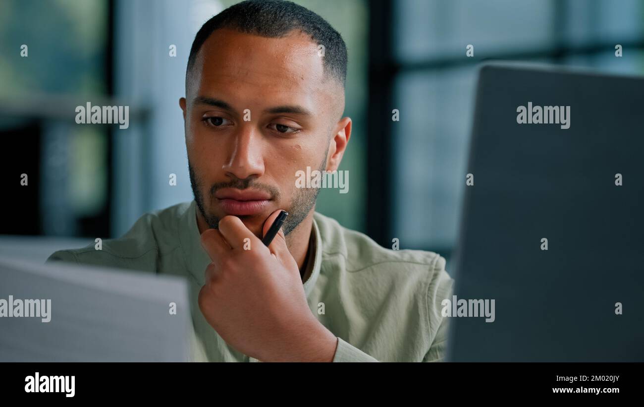 Ernsthaft nachdenklich, afrikanischer, ethnischer Geschäftsmann, Chefauditor, der die Korrespondenz von Unternehmensunterlagen überprüft, männlicher Unternehmer, der Dokumente liest, denkt Stockfoto