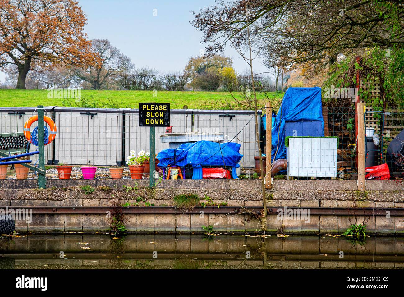 Überfüllter Anlegeplatz für schmale Boote mit „Please slow request“-Schild am Trent- und Mersey-Kanal in Cheshire, Großbritannien Stockfoto