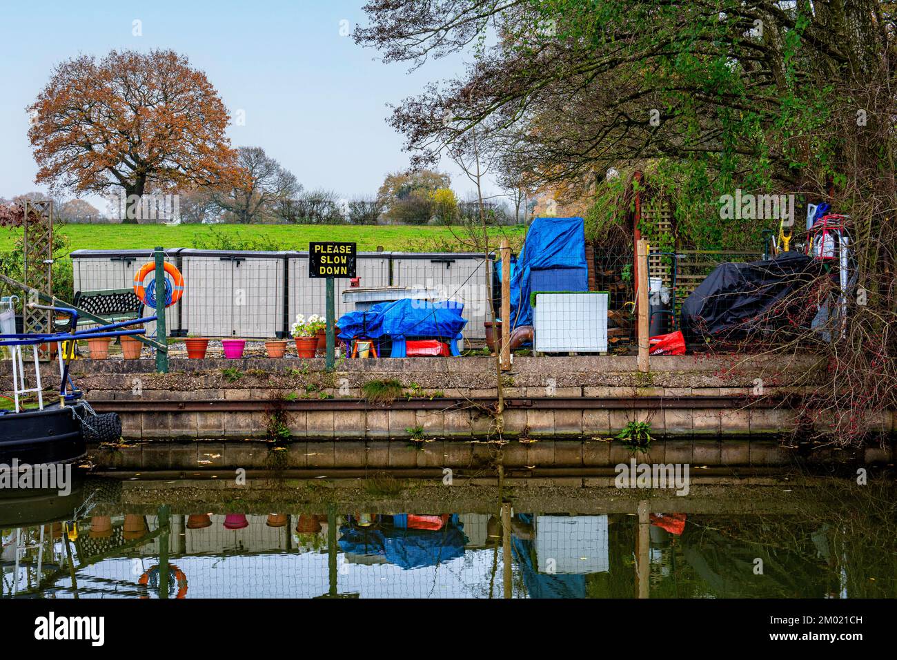 Überfüllter Anlegeplatz für schmale Boote mit „Please slow request“-Schild am Trent- und Mersey-Kanal in Cheshire, Großbritannien Stockfoto