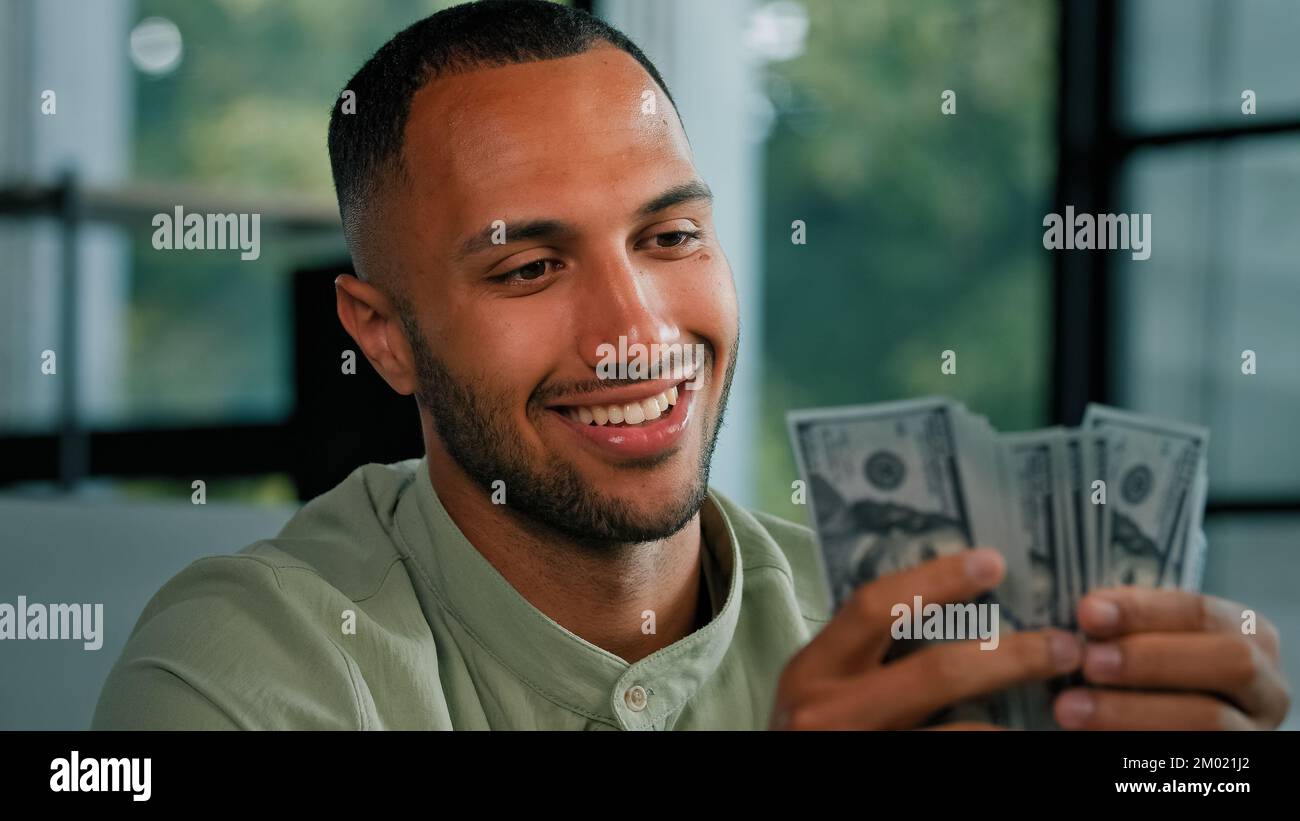 Männliches Porträt glücklich lächelnd reicher Erfolg Latein zählt Geld afroamerikanischer Geschäftsmann hält Fan von Dollarscheine Bargeld gewinnen Stockfoto