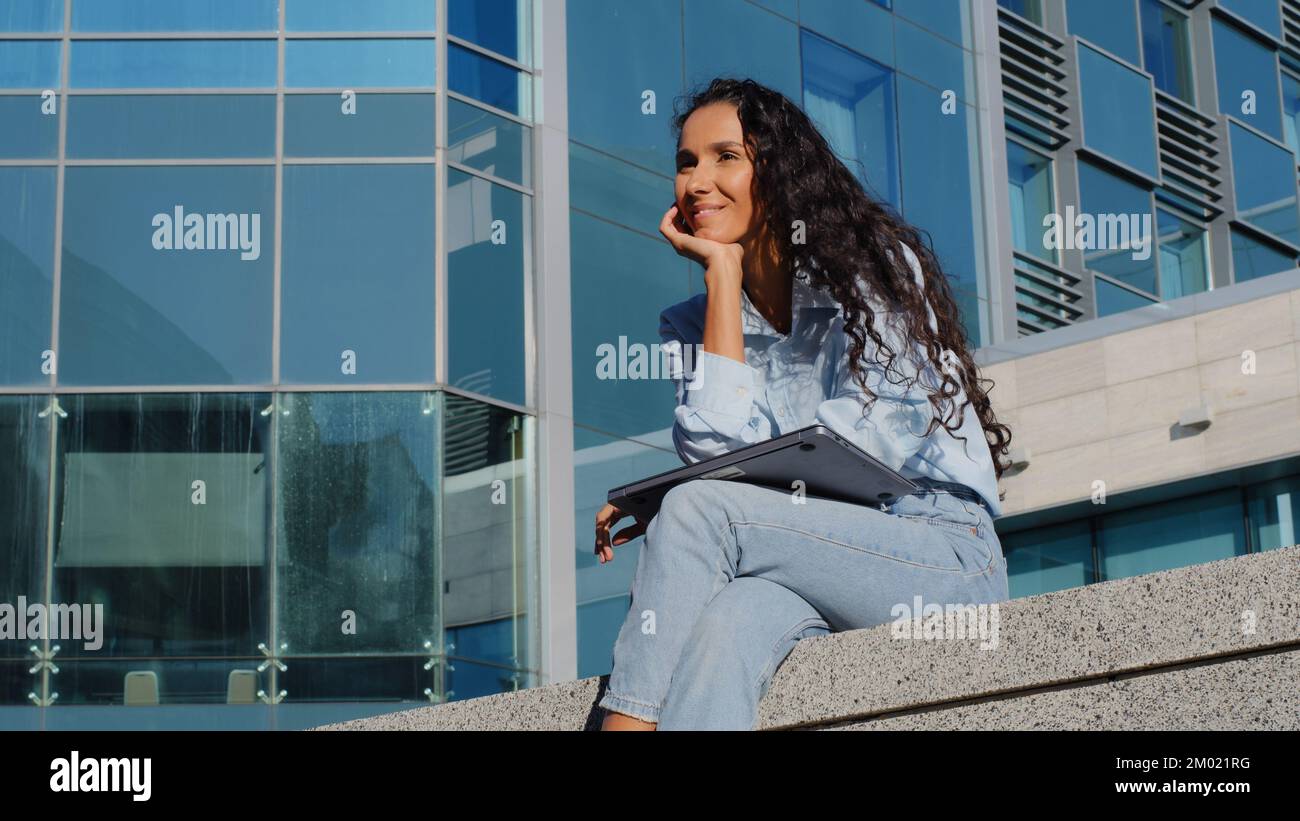 Geschäftlich entspannte Frau, die ihre Arbeit online beendet und mit einem Computer im Freien in der Stadt studiert. Mädchen schließt Laptop, hört auf zu tippen, surft, ruht sich aus Stockfoto