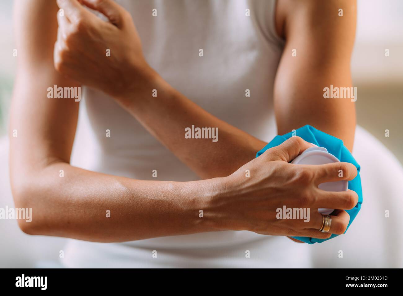 Eine Frau, die eine kalte Presse an einen Ellbogen hält Stockfoto