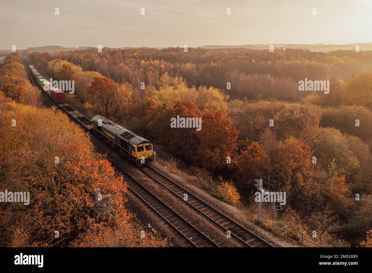 WAKEFIELD, GROSSBRITANNIEN - 2. DEZEMBER 2022. Ein britischer Freightliner Intermodal Class 66 Locomotive freight Train, der Container durch Autumnal Woodlan transportiert Stockfoto