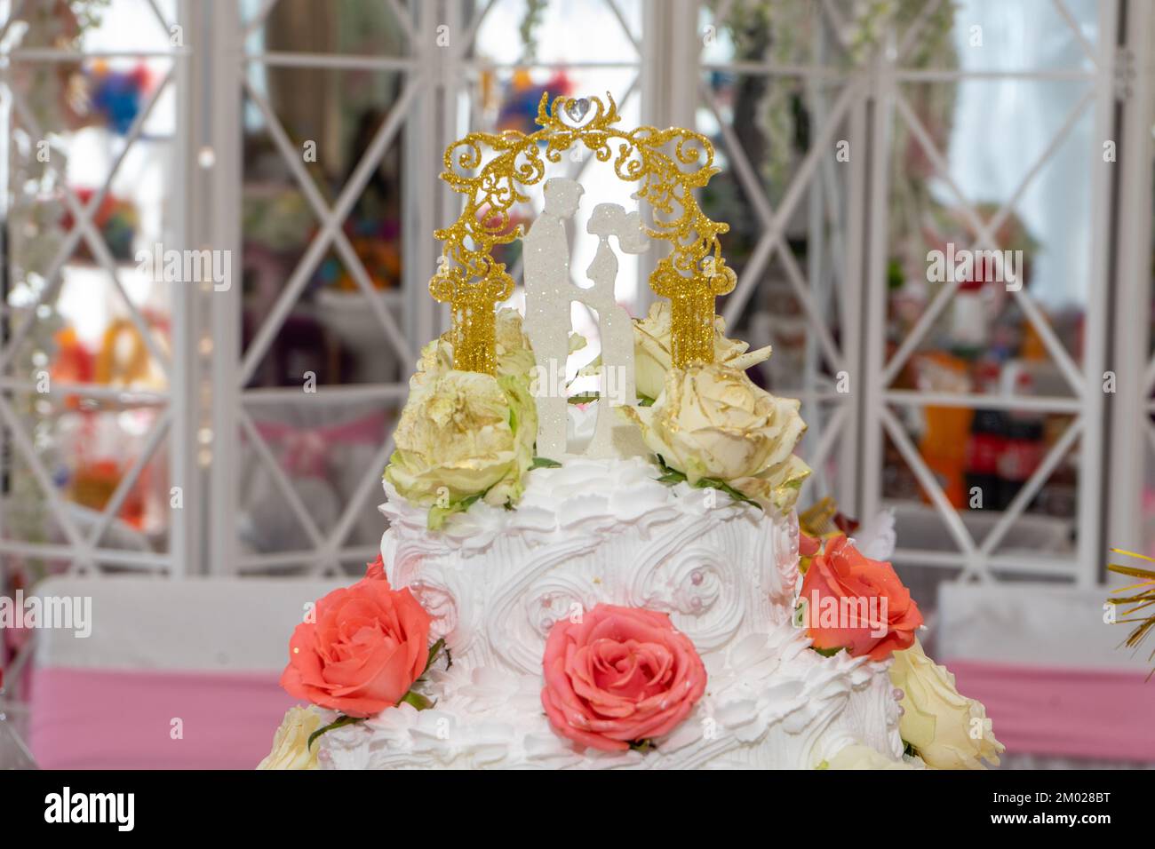 Hochzeitstorte mit Figuren von Frischvermählten und roten Rosen, Nahaufnahme Stockfoto