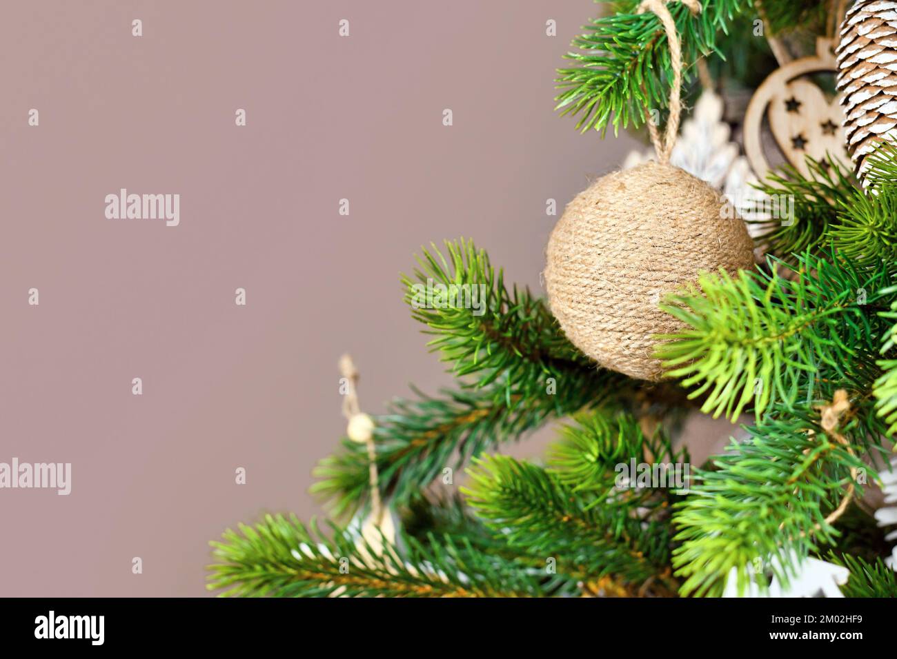 Christbaumzweige mit natürlicher Schmuckkugel aus beigefarbenem Jutegewand mit Kopierbereich Stockfoto