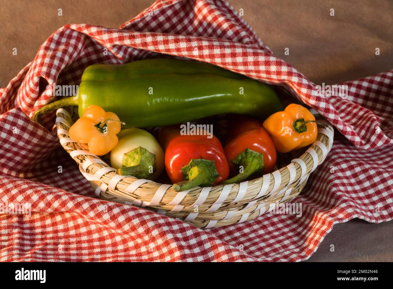 Ein Korb gefüllt mit chilenischen Paprika, einschließlich Serannos, Jalepenos und Paprika von Hatch. Stockfoto